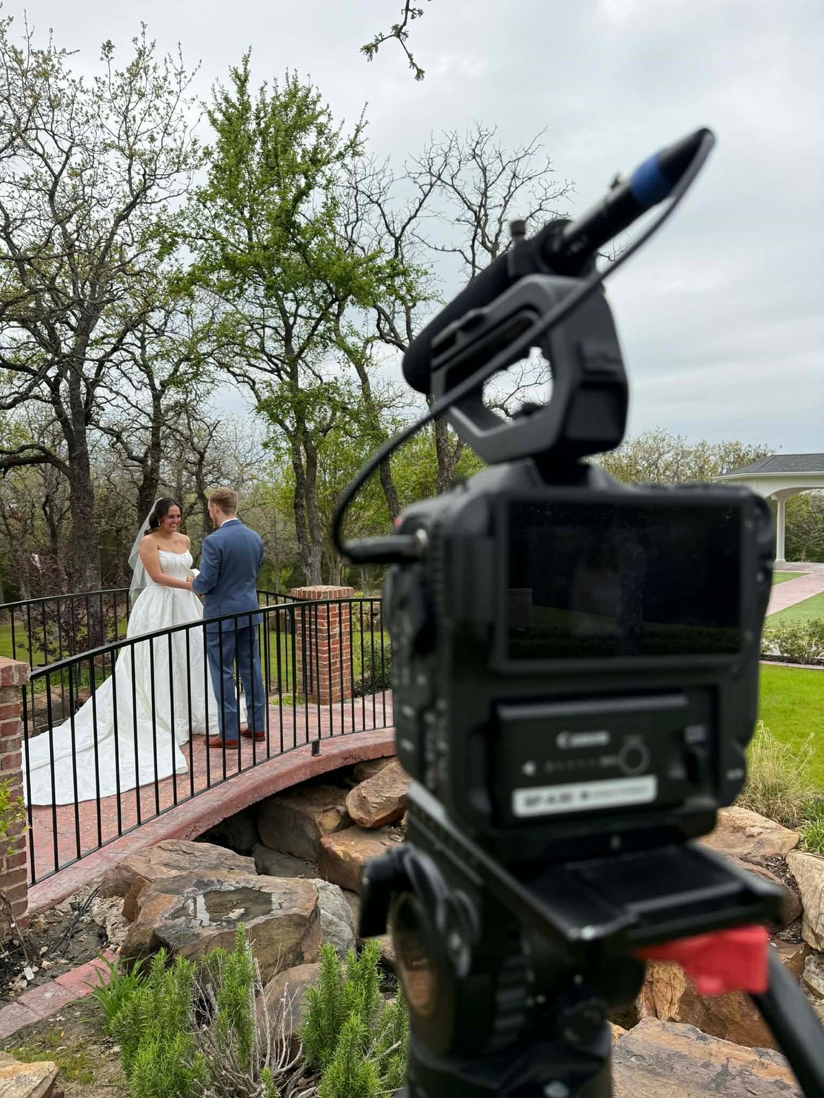 Wesley Blalock filming a bride and groom on a stone bridge with Canon cinema camera